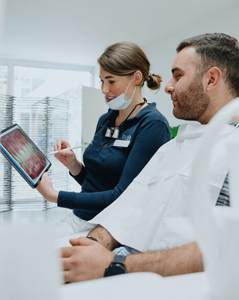 Zahnärztin Anna Rage aus Bocholt berät Patient zur ästhetischen Zahnmedizin am Tablet